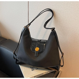 Detail of black fabric and patent leather tote bag with a golden metal ring buckle