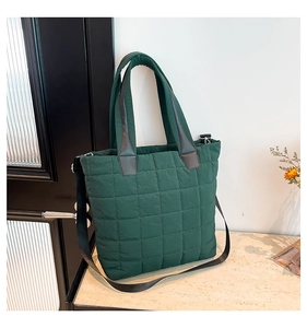 Close-up of dark green quilted tote bag showing waterproof nylon texture and leather joints