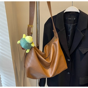 Detail view of brown large capacity hobo bag with a cute green turtle plush pendant