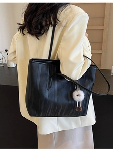 Black water-ripple faux leather tote bag with metallic logo and plush monster charm