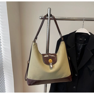 Detail of the large beige tote bag with brown patent leather trim and an N logo