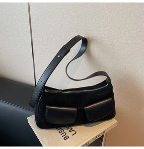 Detail of black frosted suede shoulder bag with two leather front pockets and silver zipper