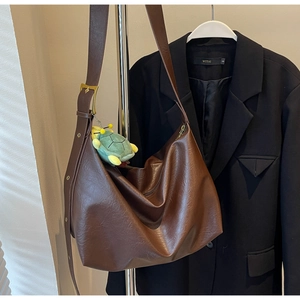 Detail view of brown faux leather hobo bag with adjustable strap and turtle charm