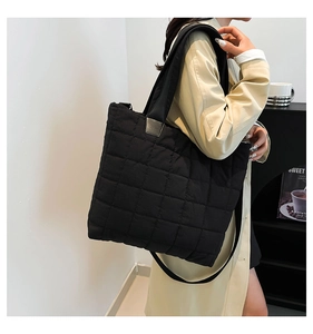 Modern black quilted nylon tote bag worn with a chic beige coat for daily styling