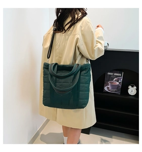 Detail of dark green quilted nylon tote bag with square stitching and adjustable strap