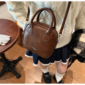 Detail view of brown leather square crossbody bag on a table with warm autumn vibes