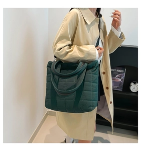 Detail of green quilted nylon tote bag with adjustable black strap shown on model
