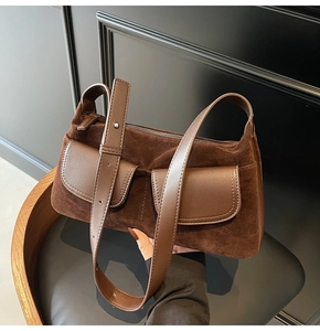 Detail of dark brown suede shoulder bag showing smooth leather flap pockets and texture