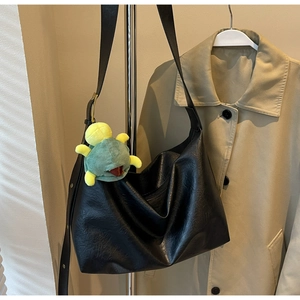 Detail view of black hobo bag with pleated texture and a cute green turtle charm