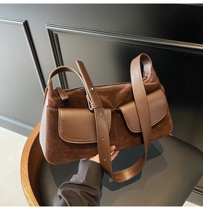 Close-up of matte suede shoulder bag with dual leather flap pockets and wide strap