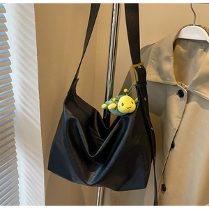 Macro detail of black faux leather tote bag with soft texture and green turtle pendant