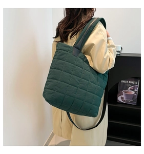Detailed view of the dark green quilted nylon tote bag worn on shoulder by a model