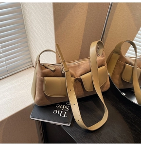 Detail of matte suede shoulder bag with dual pockets and adjustable strap in earthy tones