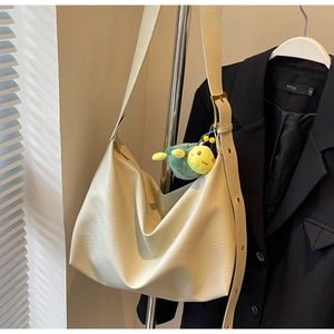 Close-up of cream leather hobo bag with gold hardware and a cute turtle plush charm