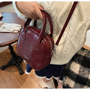 Detail of burgundy Boston bag with geometric stitching and removable shoulder strap