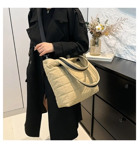 Detailed close-up of beige quilted tote bag with black and white contrast handle
