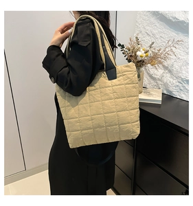 Macro detail of the oversized yellow quilted nylon tote bag with black strap contrast