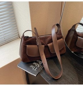 Detail of a dark brown suede hobo bag featuring two front pockets and smooth leather trim