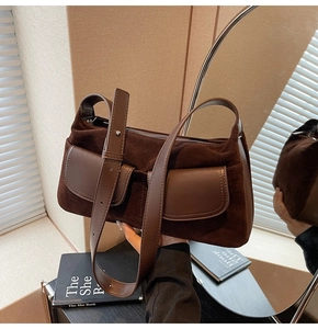 Detail of vintage brown suede shoulder bag with dual pockets and adjustable leather strap
