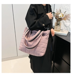 Detail of lavender quilted tote bag with black leather straps on a modern background