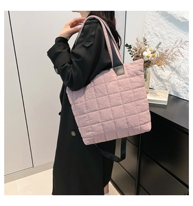 Detail of lavender quilted nylon tote bag featuring wide black handles and large square stitching
