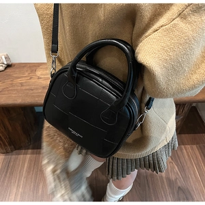 Detail view of black vintage square handbag with geometric stitching and round handles