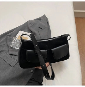 Close-up of black matte suede shoulder bag with dual front pockets and silver zipper