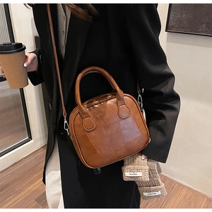 Detail of caramel brown woven leather bag with dual top handles and detachable strap