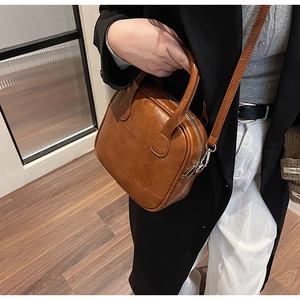 Brown vintage leather handbag with stitched quilt pattern held by a model in casual attire