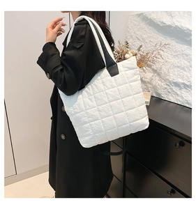Detailed side view of white quilted nylon tote bag with black leather shoulder straps