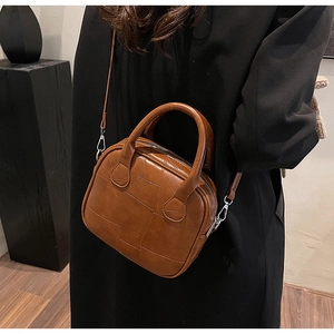 Detail of brown patchwork textured handbag with silver metal hardware and double handles
