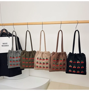 Detail of multi-color velvet bucket bags with embroidered cherry pattern and drawstring