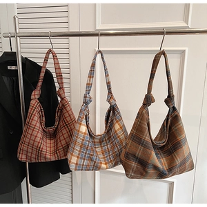 Detail of three plaid tote bags in classic checkered patterns hanging on silver hangers