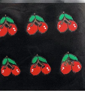 Close-up of red cherry embroidery detail on black fabric for large capacity bucket bag