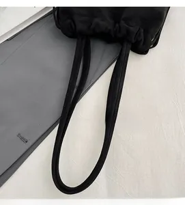 Detail of a black drawstring bucket bag with sturdy double handles and soft fabric texture