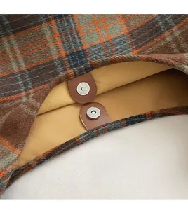Detail of wool fabric texture and dual magnetic snap closure on the plaid handbag