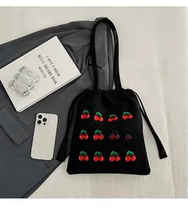 Detail of black canvas bucket bag with cherry embroidery and drawstring fringe tassel
