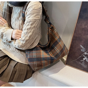 Close-up of winter plaid wool shoulder bag with unique knot strap on a stylish outfit
