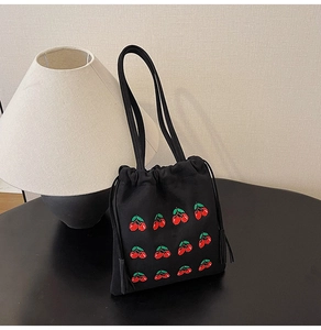Detail of cherry embroidery on black canvas drawstring bucket bag with tassels