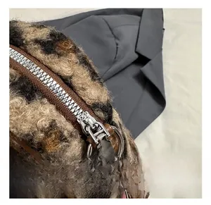 Detail of leopard print faux fur texture with smooth metal zipper and brown leather piping