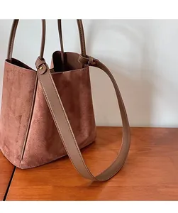 Détail de la longue bandoulière lisse d'un sac seau en daim marron de style vintage