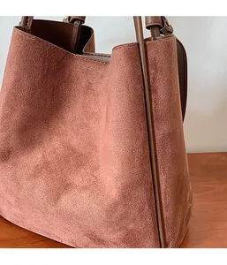 Gros plan du sac cabas en daim marron montrant la texture douce et la poignée fine