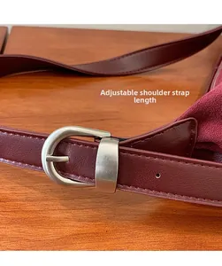 Close-up of adjustable wine red leather shoulder strap with a matte silver buckle detail