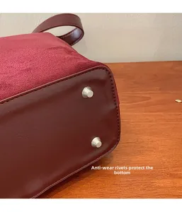 Detail view of burgundy PU leather bag bottom with silver protective metal studs