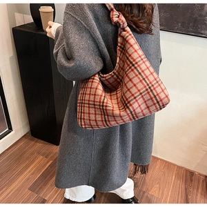 Detailed back view of a model wearing a large plaid tote bag with twisted knot handles