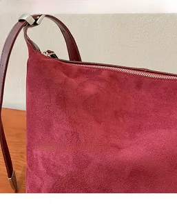 Close-up of wine red faux suede texture with silver zipper detail on large shoulder bag