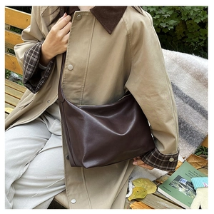 Deep brown large hobo shoulder bag shown on model in a warm autumn outdoor setting