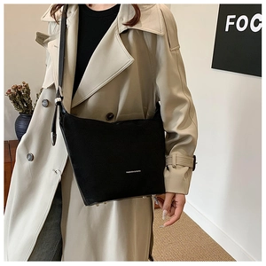 Detail of minimalist black bucket bag with white fashion text on chic beige trench coat