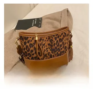 Detail show of leopard print bucket bag with side leather tassels and wide shoulder strap