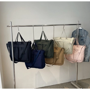Detail of multi-color nylon tote bags showing large front pockets and adjustable straps